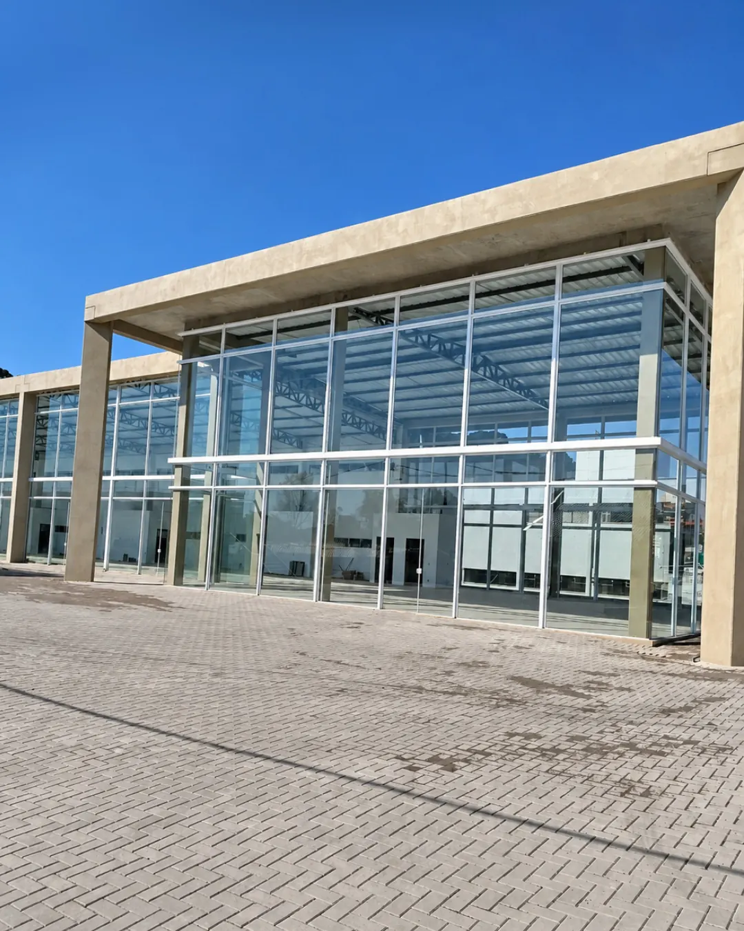 Pátio em paver na frente de prédio comercial envidraçado